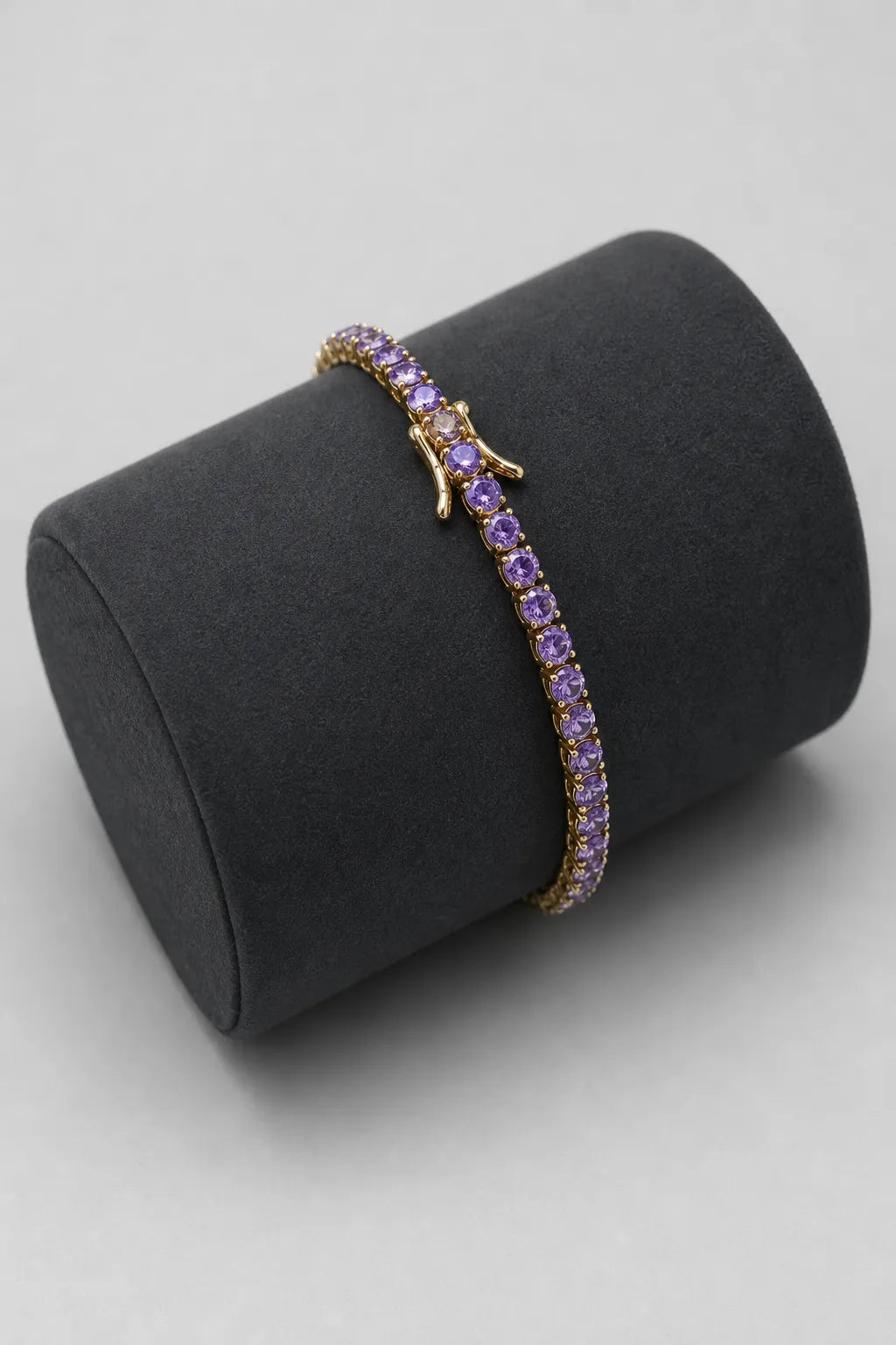 Purple Tennis Bracelet — Gold-tone, purple stones — on a display cushion