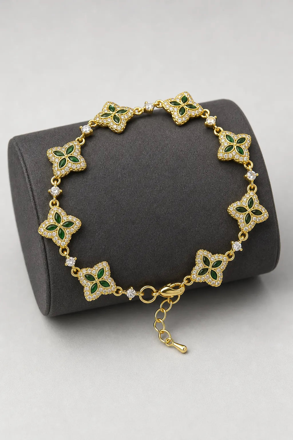 Flower Tennis Bracelet — Gold-tone with green centres (primary) — on a display cushion