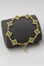 Flower Tennis Bracelet — Gold-tone with green centres (primary) — on a display cushion