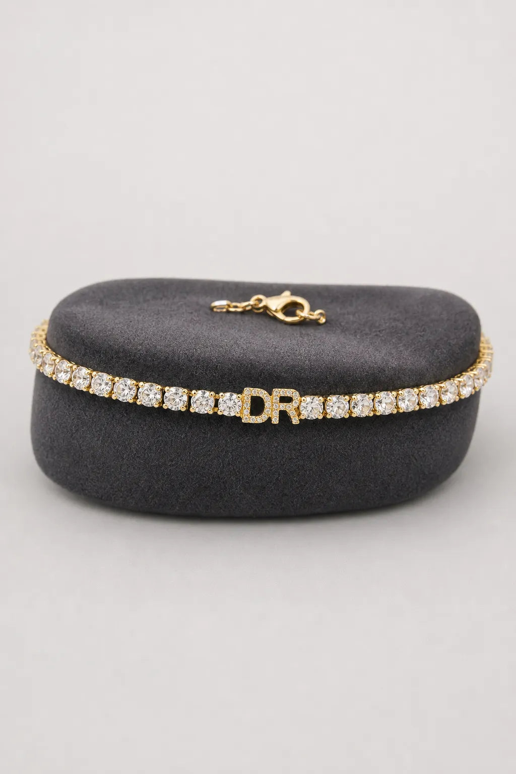 Personalized Tennis Bracelet — Gold-tone with clear stones, DR example — on a display cushion