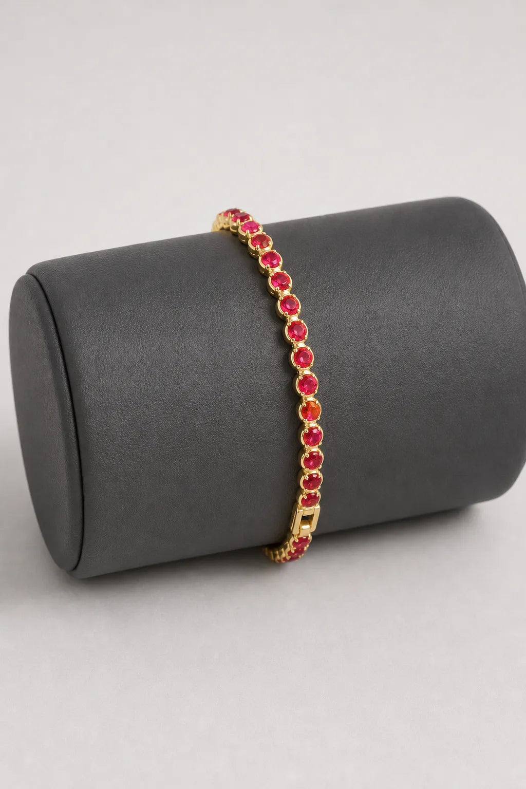 Red Tennis Bracelet — Red stones — gold-tone metal — on a display cushion