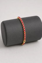 Red Tennis Bracelet — Red stones — gold-tone metal — on a display cushion